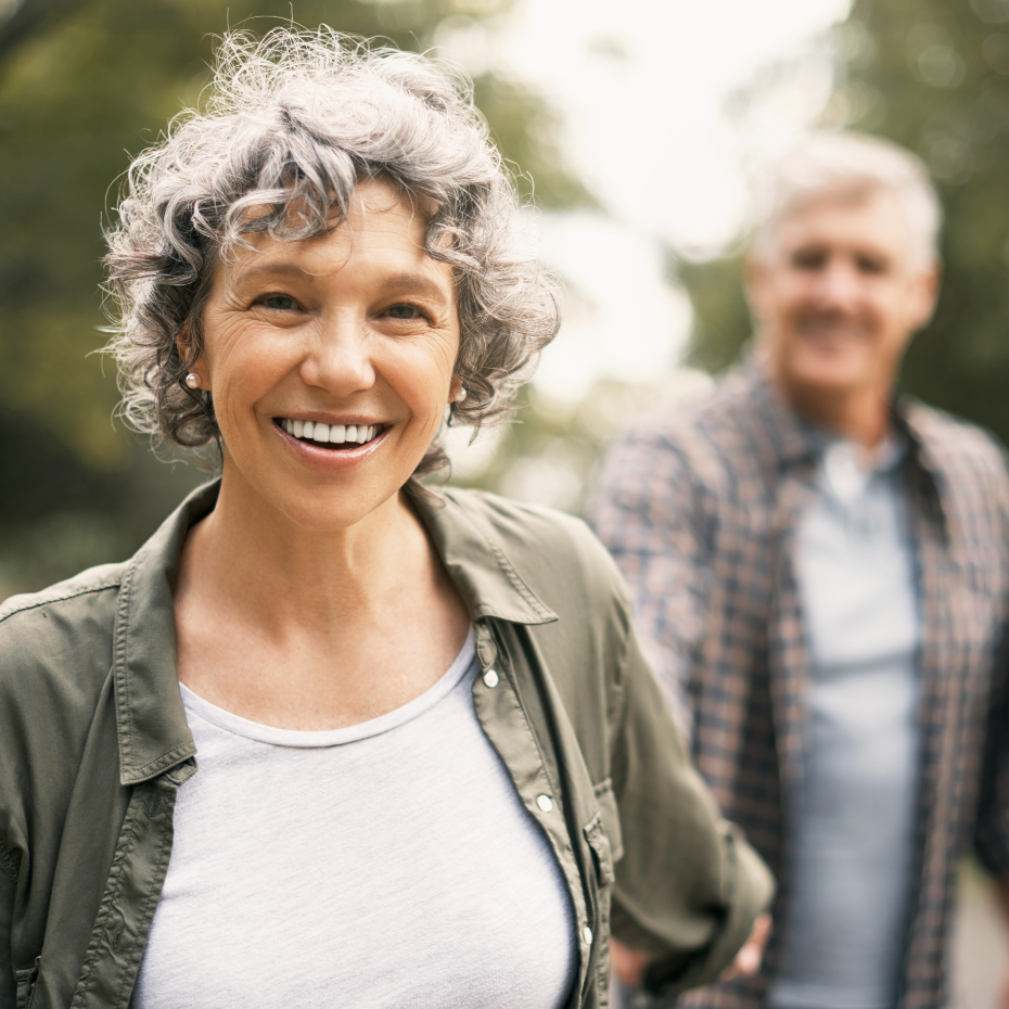 Älteres Paar läuft händchenhaltend durch den Park.
